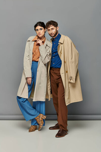 trendy couple in trench coats, fashion shot, man and woman, outerwear, grey background, style