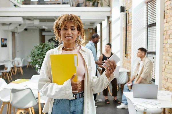 stock image happy african american woman with braces holding smartphone and folder, startup, gen z, coworking