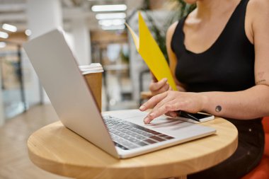 Bir kadının dizüstü bilgisayar kullanması, klasörü tutması, başlangıç projesinde çalışması, birlikte çalışması, aygıtlar