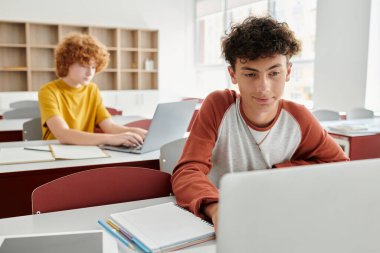 Okula dönmek, sınıfta dizüstü bilgisayar kullanan gençler, e-öğrenim, eğitim, sınıf arkadaşları ve aletler.