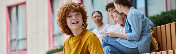 banner, happy redhead boy with curly hair looking at camera, blur, diversity, students and teacher