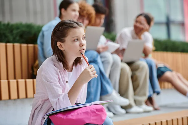 学校に戻って ペンシルベニアの女の子が 口の近くで鉛筆を握り メモを取ったり 考えたり ぼやけたり 研究したり — ストック写真