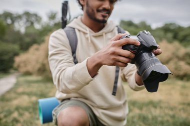 Profesyonel kamera, doğal mekan ve seyahat kullanan neşeli Hintli fotoğrafçı görüntüsü.