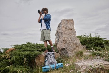 fotoğraf ve doğa konsepti, Hintli sırt çantası dijital kameraya çekiliyor ve kaya üzerinde duruyor.