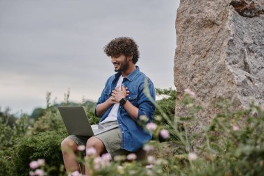 Dijital göçebe konsepti, neşeli Hintli serbest yazar dizüstü bilgisayarında doğal konumda video çağrısı yapıyor.