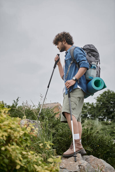 travel photographer concept, curly indian man taking photo on digital camera during journey, nature