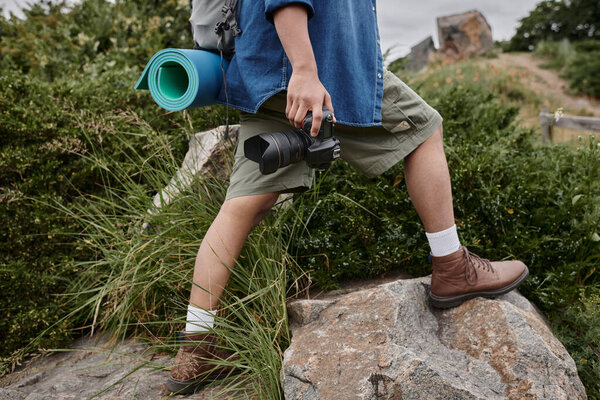 travel and photography concept, cropped view of man holding camera and walking in natural place