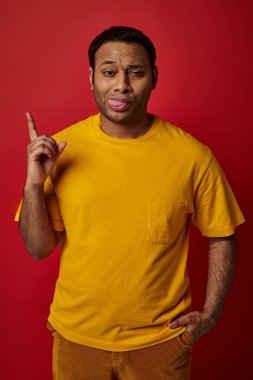 face expression, emotional man sticking out tongue and pointing up on red background, grimace clipart