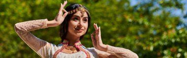 Yaz tatili, otantik giyinmiş esmer Hintli kadın gülümsüyor ve parkta poz veriyor.