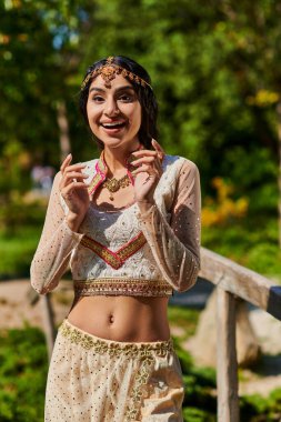 Yazlık parkta güneşli bir günde geleneksel kıyafetleriyle kameraya bakan Hintli kadına hayran kaldım.