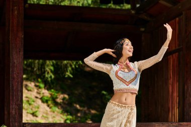 Geleneksel Hintli kadın aşırı neşeli ve şaşkın Yazın uzakta bakıyor ve parkta dans ediyor