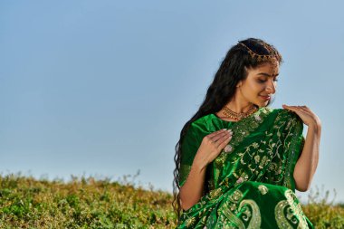 Genç Hintli kadın, Matha Patti ile Tepede yeşil sari 'ye dokunuyor.
