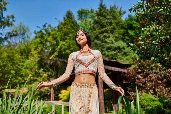 夏の公園での散歩を楽しむ閉じた目を持つ本格的なスタイルのインドの女性を喜ばせます — ストック写真