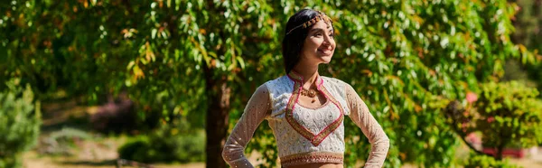 身穿民族服装的印度妇女微笑着 双手叉腰站在那里 望向远方的公园 高举横幅 — 图库照片
