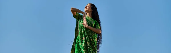 阳光明媚的日子 穿着莎丽服的印度女人 站在蓝天下闭着眼 高举横幅 — 图库照片