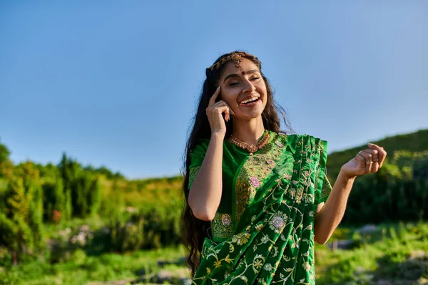 Veselá Mladá Indická Žena Dotýkající Obličeje Při Pózování Sari Krajinou — Stock fotografie