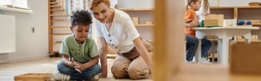 Montessori materyali, Afrikalı Amerikalı çocuk mutlu öğretmen pankartın yanında eğitici renk oyunu oynuyor.