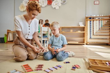 montessori school, female teacher sitting near blonde boy and showing wooden toys, educational game clipart