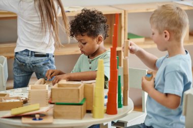 Montessori oyunu oynayan ırklar arası çocuklar, Afrikalı Amerikalılar, tahta oyuncaklar, renk eşleşmesi