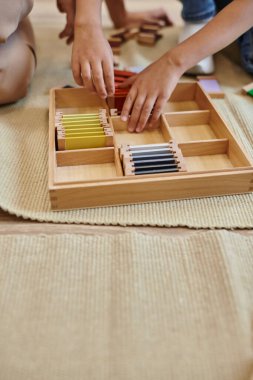 Montessori okulu konsepti, kadın öğretmenin yanında renk eşleştirme oyunu oynayan kız, kırpık manzara