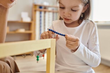 Montessori konsepti, renkli boncuk merdivenlerle oynayan kız öğretmen, ahşap tezgah, kapatın.