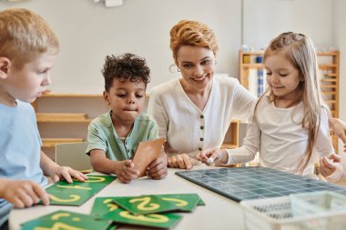 Sayıları saymayı öğrenen mutlu ırklar arası çocuklar ve kadın öğretmen, Montessori okulu.