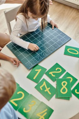 Tahtaya numara yazan bir kızın Montessori okulunda sayı saymayı öğrenmesi.