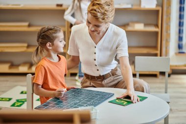 Güzel kız oyun, matematik, sayma, karatahta, kadın öğretmen, Montessori okulu ile öğreniyor.