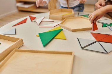 Montessori okulunda üçgenlerle oynayan öğretmen ve çocuk manzarası
