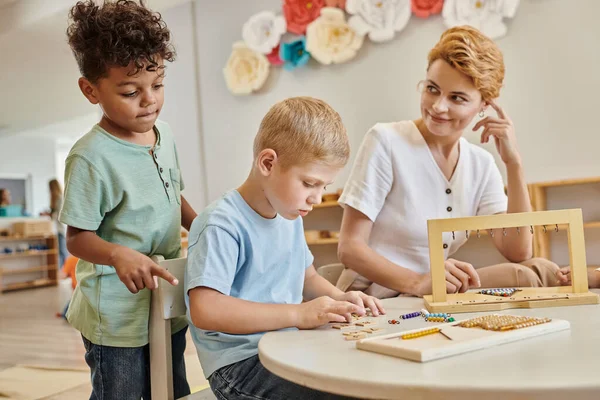 Szkoła Montessori Szczęśliwy Nauczyciel Obserwując Międzyrasowe Dzieci Gra Edukacyjna Różnorodnych — Zdjęcie stockowe
