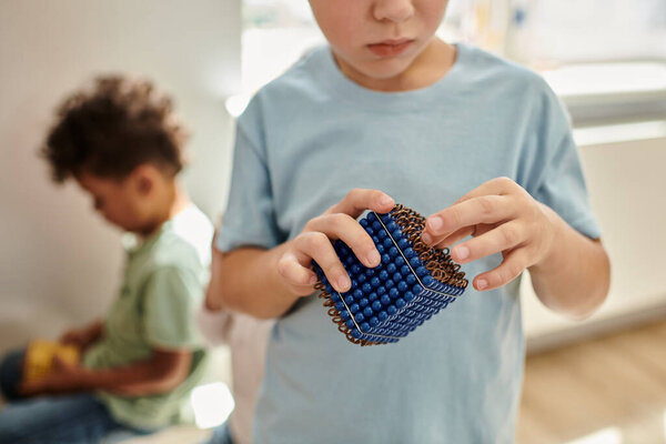 крупным планом, умный мальчик держит Монтессори жемчужные бусины материал, узнать математику, размытый фон