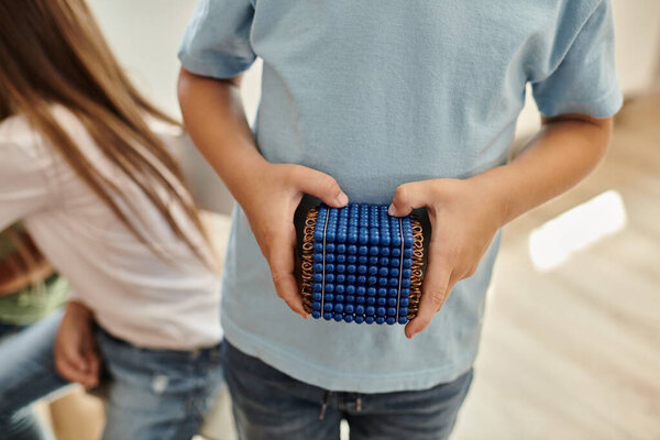 обрезанный вид, умный мальчик держит Монтессори жемчужные бусы материал, учиться математике, размытый фон