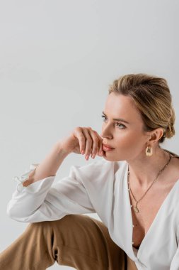 Resmî pastel elbiseli güzel bir kadın yüzüne dokunuyor, moda.