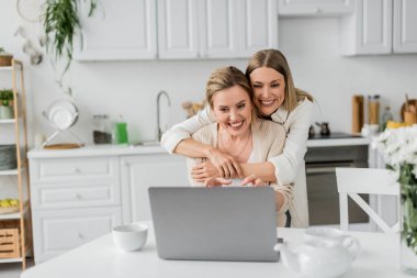 Sırtından gülümseyen ve sarılan sarışın kız kardeşler, aile bağları.