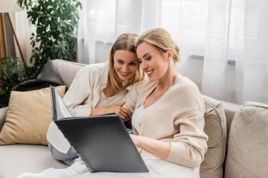 İki neşeli genç kız kardeş kucaklaşıyorlar ve fotoğraf kitabına bakıyorlar, aile bağı.