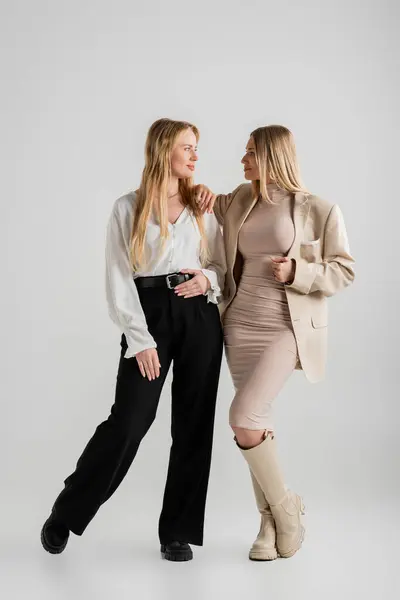 迷人的时髦姐妹们相互望着对方 在灰色的背景上摆出一副很时髦的姿势 — 图库照片