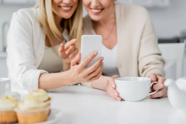 stock image cropped view of pretty classy sisters making selfie and smiling on kitchen background, bonding