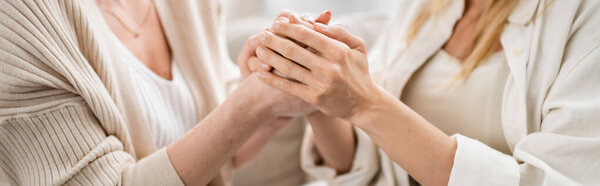 cropped view of blonde good looking sisters in lovely casual outfits holding hands, bonding, banner