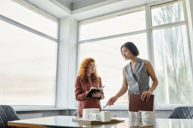 entrepreneur pointing at building model near redhead architect with notebook, startup presentation clipart