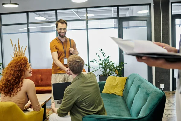 stock image happy bearded entrepreneur shaking hands with colleague near young businesswomen in office