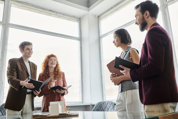 молодые архитекторы демонстрируют бизнес-партнерам в офисе архитектурный проект, концепцию стартапа