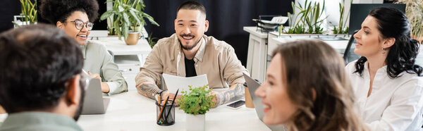 весёлые мультикультурные бизнесмены обсуждают проект и мозговой штурм рядом с лидером команды, баннером