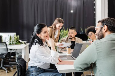 Neşeli ekip, ofisteki çok kültürlü iş adamlarının yanında Hintli iş arkadaşının fikirlerini dinliyor.
