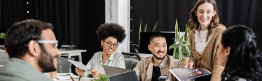 happy interracial business team looking at team leader on blurred foreground, brainstorming banner clipart