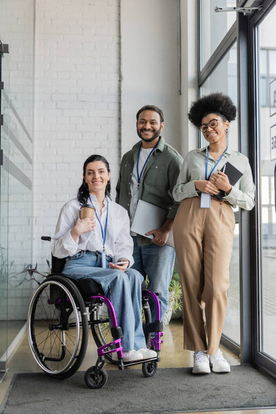 group shot of diverse business people looking at camera, disabled woman on wheelchair and colleagues