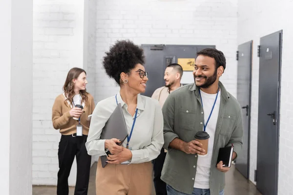 stock image happy african american woman and indian man chatting during coffee break near diverse colleagues