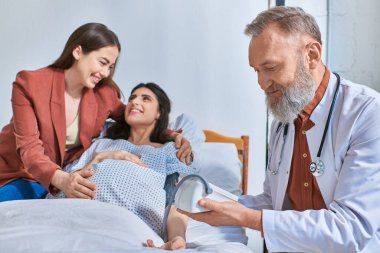 joyous lgbt couple smiling cheerfully at each other while doctor measuring pressure, ivf concept clipart