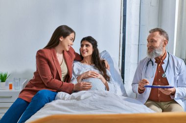Tüp bebek konseptinde birbirlerine sarılan neşeli Igbt çifti.