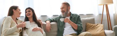 lgbt couple and father of one of them sitting on sofa laughing and drinking tea, ivf concept, banner clipart