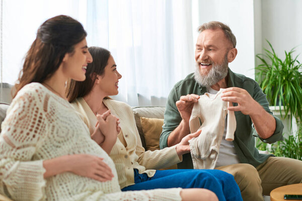 happy lgbt couple getting singlet as present from grey bearded father of one of them, ivf concept
